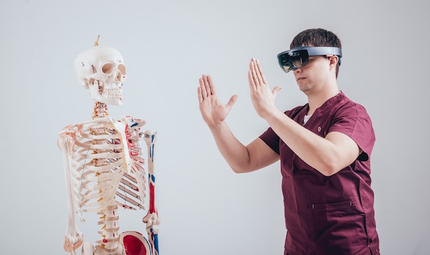 El doctor usa gafas de realidad aumentada para examinar el esqueleto humano
