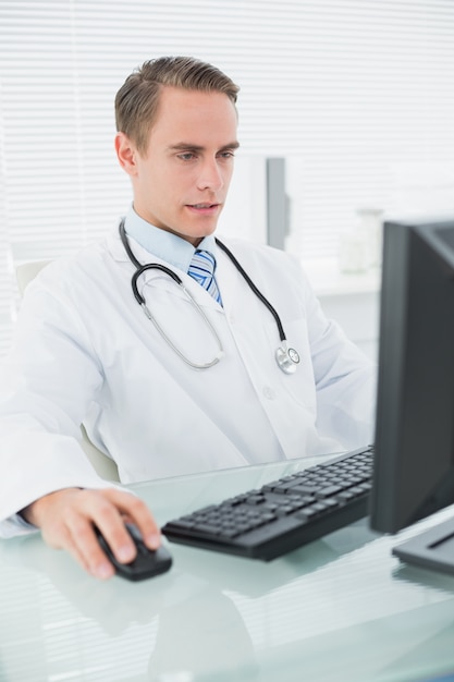 Foto doctor usando la computadora en el consultorio médico