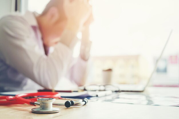 Foto doctor usando una computadora portátil mientras está sentado en el escritorio en la oficina