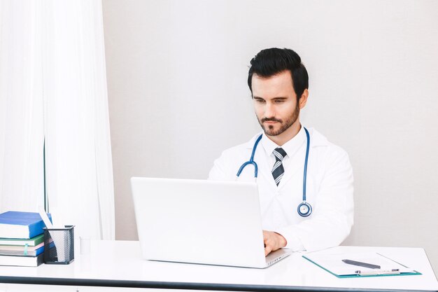 Foto doctor usando una computadora portátil mientras está sentado en la oficina