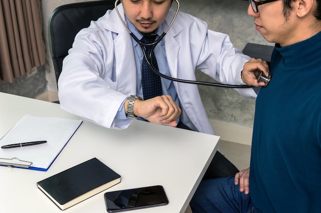 Doctor usando estetoscopio para controlar la frecuencia cardíaca y consultar con el paciente