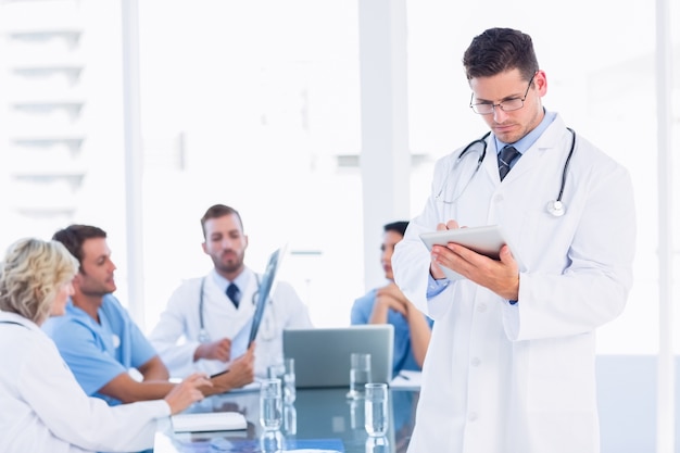 Doctor usando tableta digital con colegas en reunión