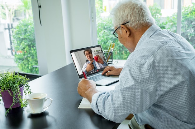 Doctor en video conferencia en línea con el paciente anciano para monitorear y preguntar por los síntomas de la enfermedad y brindar asesoramiento y consulta del concepto de atención médica, telemedicina y telesalud.