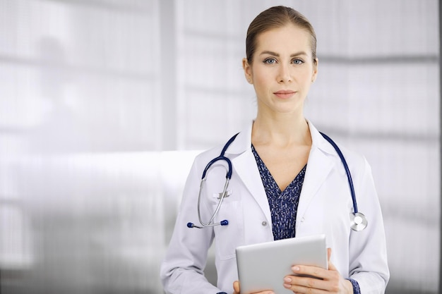 Doctora alegre parada en la clínica. Retrato de una amigable y sonriente médica. Servicio médico perfecto en el hospital. Concepto de medicina.