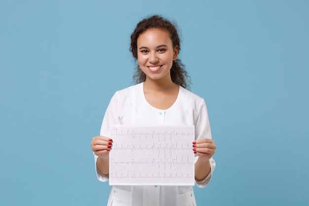 Foto una doctora americana sonriente con bata médica tiene un registro de electrocardiograma, gráfico de onda de electrocardiograma cardíaco en papel aislado en fondo azul. concepto de medicina del personal sanitario. simulacros de espacio de copia.