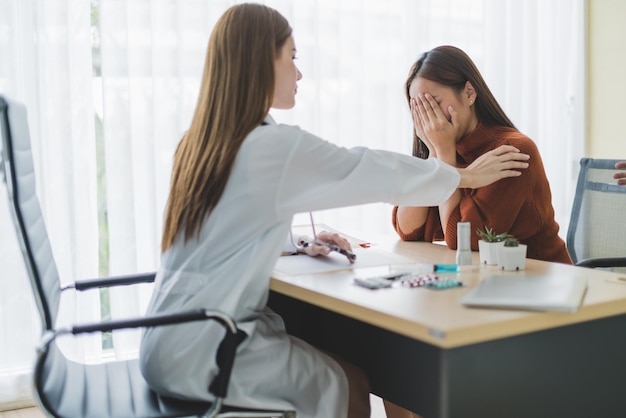 Una doctora asiática alienta y apoya a la paciente cansora después de consultar y examinar en el concepto de ideas de salud del hospital clínico