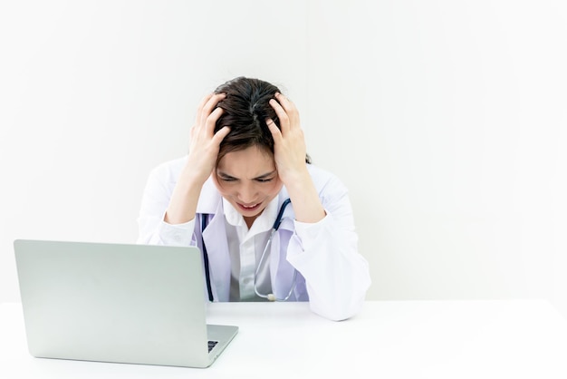 La doctora asiática sentada en el escritorio está estresada y cansada del trabajo duro para cuidar a los pacientes