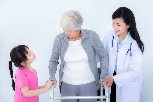 Doctora ayudando a la mujer mayor mediante el uso de andador y su nieta. Cuidado de pacientes mayores y cuidado de la salud, concepto médico.