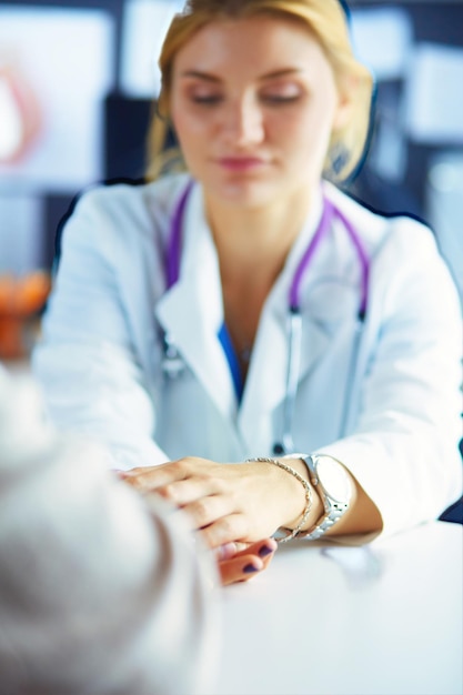 Doctora ayudando a senior de la mano en el hospital