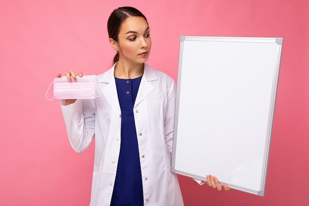 Doctora en una bata médica blanca con tablero en blanco