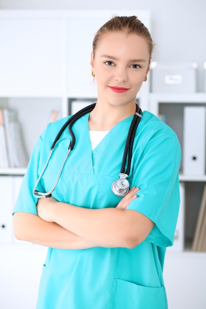 La doctora cirujana está de pie con los brazos cruzados y sonriendo en el hospital. Médico listo para examinar al paciente