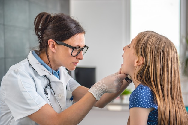 Doctora comprobando la garganta de la niña