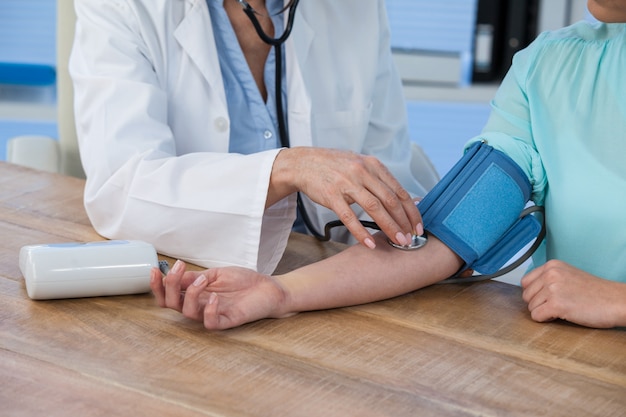 Doctora comprobando la presión arterial de un paciente