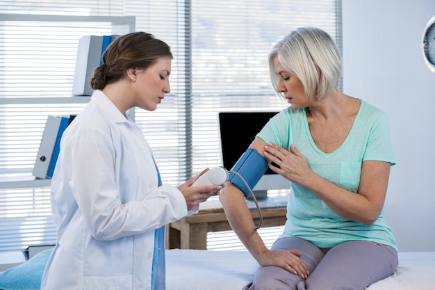 Doctora comprobando la presión arterial de un paciente