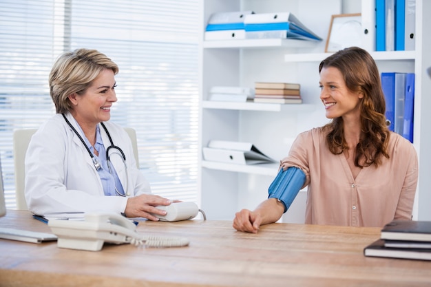 Doctora comprobando la presión arterial de un paciente