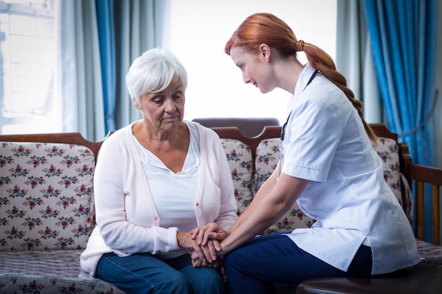 Doctora consolando a mujer senior en la sala de estar