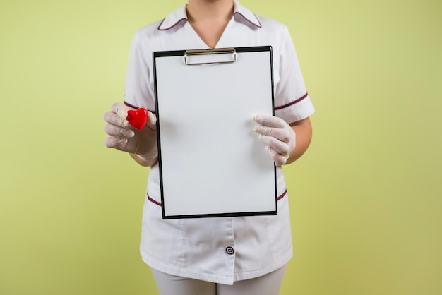 Doctora con corazón rojo y portapapeles en blanco aislado sobre fondo blanco.