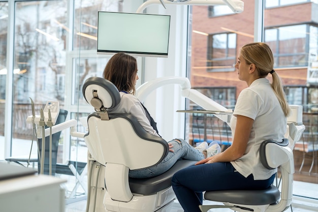 Una doctora dentista y una clienta están hablando durante una consulta en una clínica dental