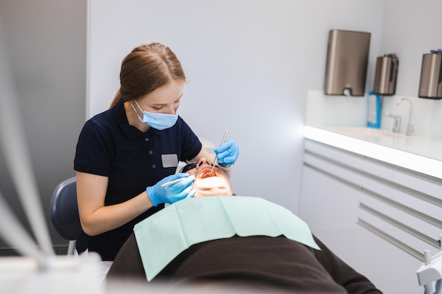 Doctora dentista examina los dientes de un paciente masculino