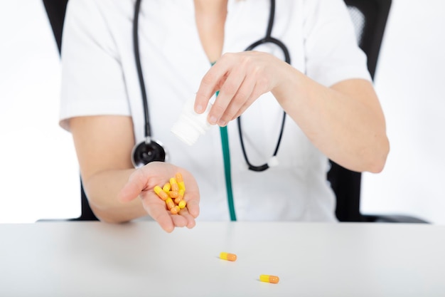 Doctora, enfermera en su escritorio vertiendo pastillas en su mano.