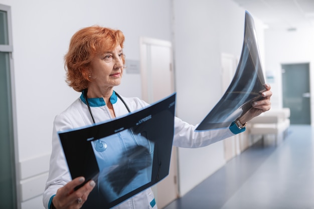 Doctora enfocada examinando radiografías de los pulmones de un paciente