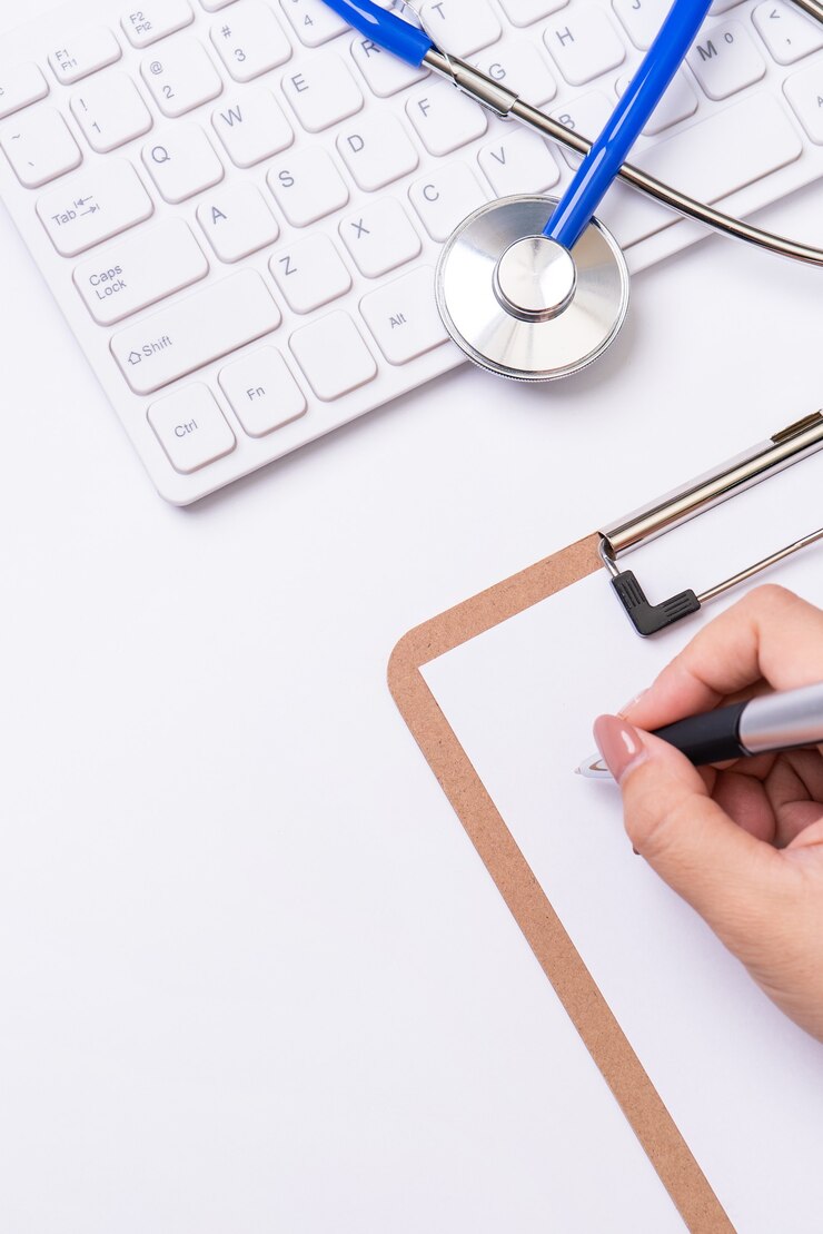 Foto doctora escribiendo un caso de registro médico sobre el portapapeles en la mesa de trabajo blanca con estetoscopio, teclado de computadora