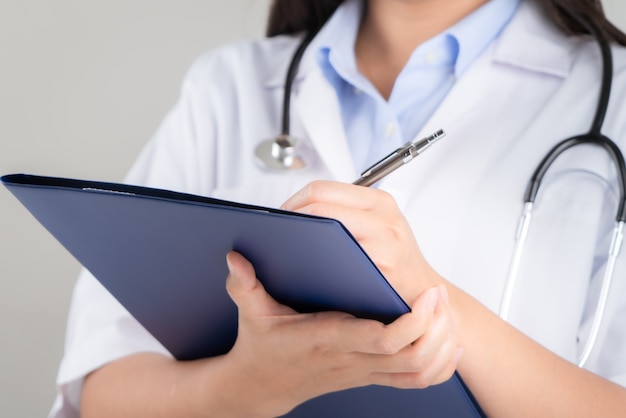 Doctora escribiendo información médica en el cuaderno en el hospital