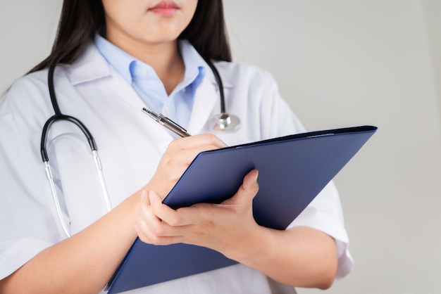 Doctora escribiendo información médica en el cuaderno en el hospital