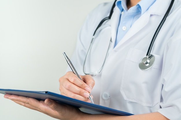 Doctora escribiendo información médica en el cuaderno en el hospital