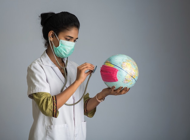 Doctora escuchando el globo terráqueo con estetoscopio