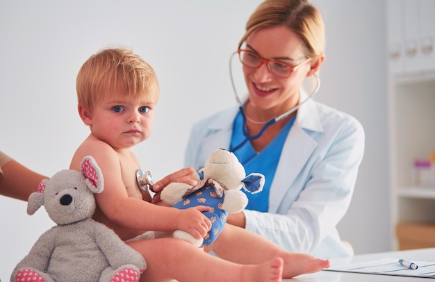 Doctora está escuchando a un niño con un estetoscopio en la clínica