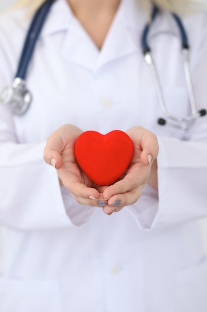 Foto doctora con estetoscopio con corazón. pareja de pacientes sentada en el fondo