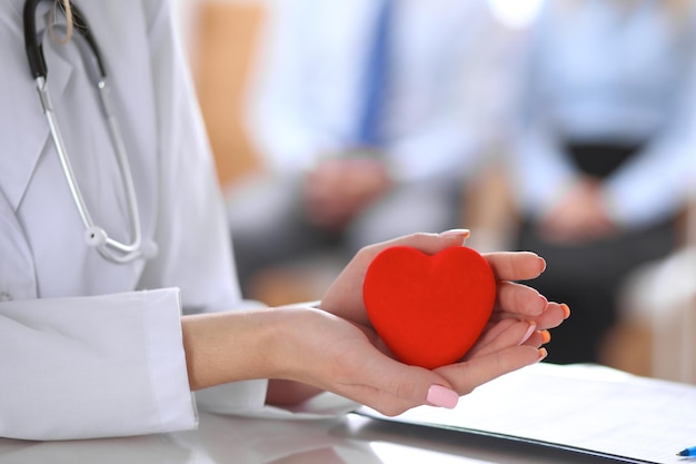 Doctora con estetoscopio con corazón. Pareja de pacientes sentada en el fondo