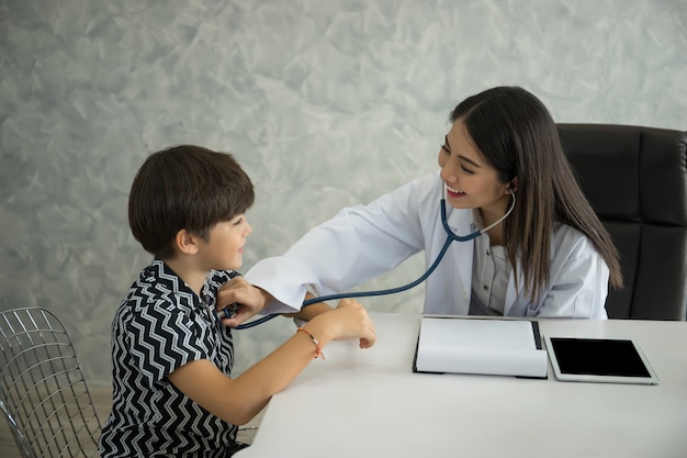 Doctora con un estetoscopio examinando a un niño en el hospital.