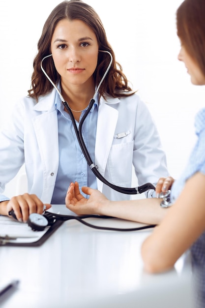 Foto doctora con un estetoscopio en la mano examinando a su paciente. conceptos de salud, cardiología y medicina.