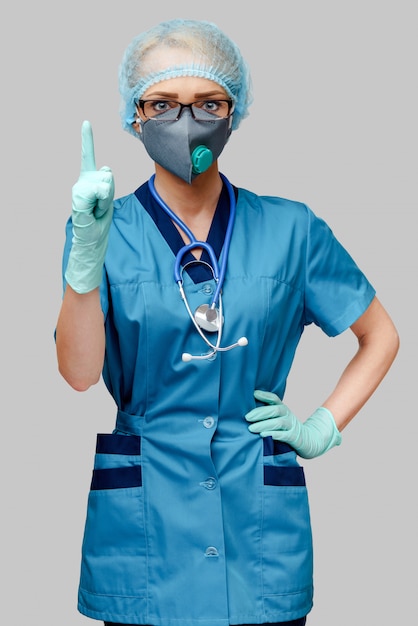 Doctora con estetoscopio con máscara protectora y guantes de látex sobre fondo gris claro
