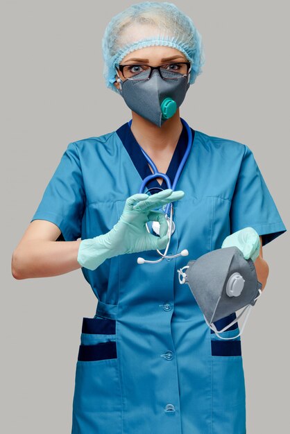 Doctora con estetoscopio con máscara protectora y guantes de látex sobre pared gris claro