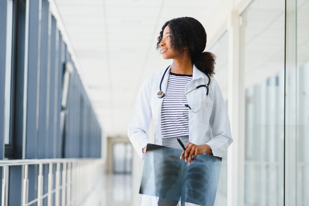 Doctora con estetoscopio en el pasillo del hospital con portapapeles con un quirófano en el fondo, concepto médico y sanitario, enfoque selectivo.