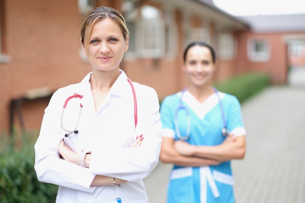 Doctora con estetoscopio de pie cerca de la clínica médica