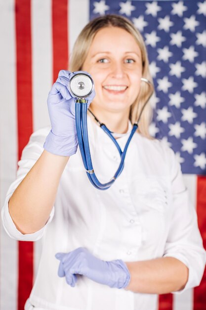 Doctora con estetoscopio sobre un fondo de bandera de estados unidos