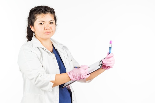 Doctora con un estetoscopio sosteniendo una botella médica sobre un fondo blanco.