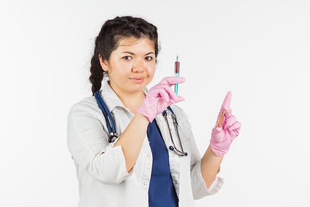 Doctora con un estetoscopio sosteniendo una botella médica sobre un fondo blanco.