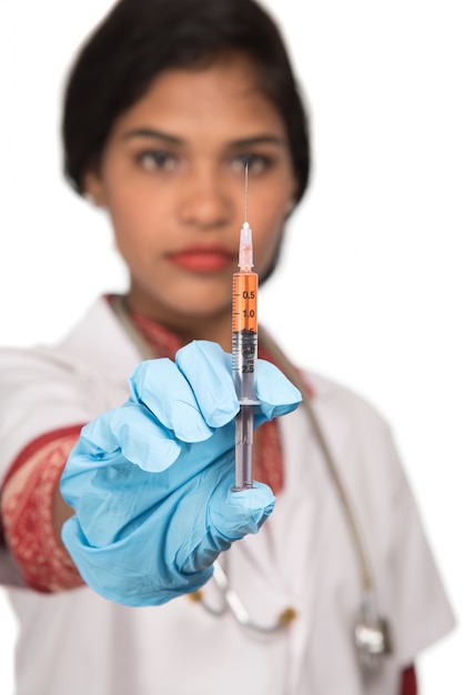 Una doctora con un estetoscopio sostiene una inyección o una jeringa.