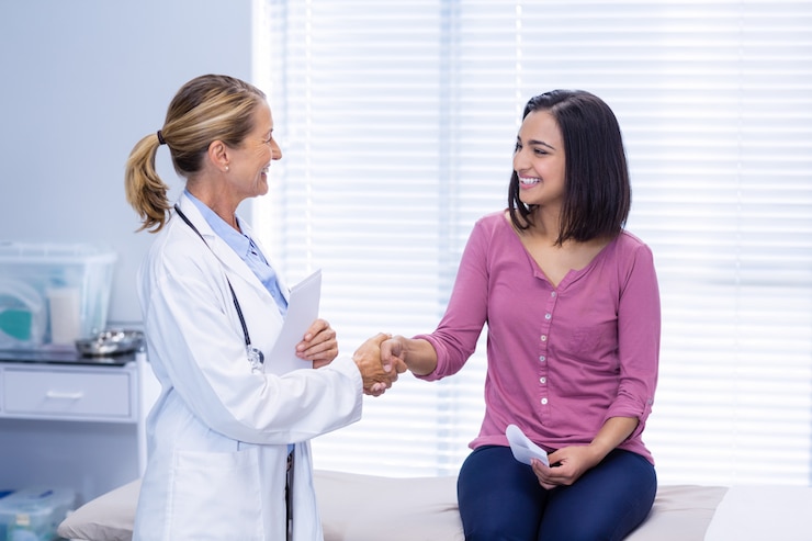 Foto doctora estrechándole la mano con el paciente