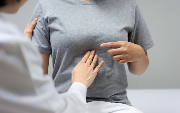 Foto la doctora está examinando por palpación abdominal de una paciente sentada en la cama dentro de la clínica.