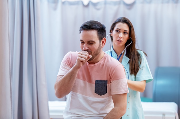 Foto doctora examinando los pulmones del paciente con estetoscopio.