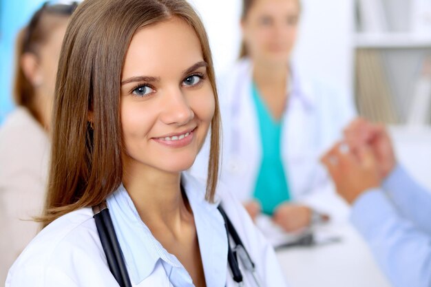 Doctora feliz con personal médico en el hospital sentado en la mesa y discutiendo el historial médico