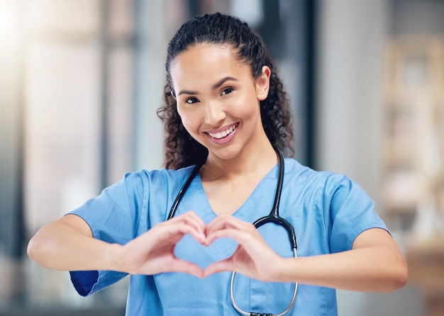 Foto doctora feliz y retrato con las manos del corazón por amor en la atención médica o el seguro de vida en el hospital persona femenina o profesional médico que muestra el símbolo o signo emoji amoroso de la mano en la clínica