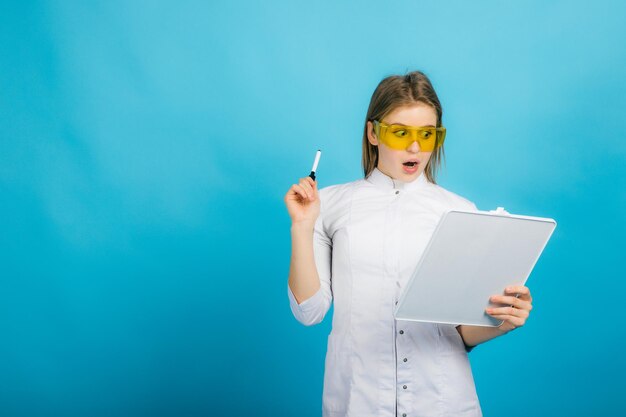 Doctora en gafas amarillas y escritorio sobre fondo azul.