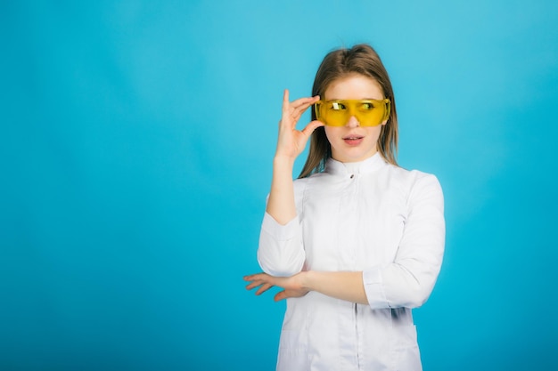 Doctora en gafas amarillas sobre fondo azul.